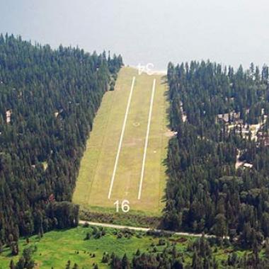 Sullivan Lake State Airport runway inbetween the forest with a body of water right before landing.
