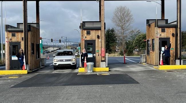 Three people standing outside three separate toll booths at Mukilteo terminal